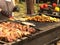 A man is cooking barbecue on an open fire. The cook flips the baked fish. Grilled meat and ribs. Fatty high-calorie foods with
