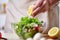 Man cooking at kitchen making healthy vegetable salad, close-up, selective focus.