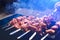 Man cooking marinated shashlik, lamb meat grilling on metal skewer, blue smoke, Sale. Close up. Defocused