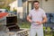 Man cooking meat on barbecue in the backyard of the house. Handsome man preparing barbecue salmon fillet. Barbecue chef