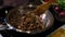 A man cooks mushrooms in a large iron frying pan on an electric stove