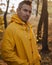 A man with a cool hairstyle in a yellow raincoat in an autumn Park