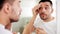 Man with cotton pad cleaning face at bathroom