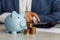 Man is counting profit on a calculator, piggy bank and coins on wooden desk in office. Economy and management financial