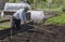 The man in the country makes the holes for planting potatoes .