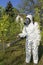 Man in Coveralls With Gas Mask Spraying Orchard With Backpack Atomizer Sprayer