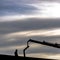 Man and crane silhoutted against sky in Daybreak