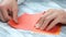 Man creating origami with red paper close up.