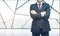 A man with crossed hands stands in a conpeorary office space with New York panoramic view.