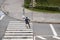 Man crosses the road at a pedestrian crossing and carries a bicycle next to him. View from above.