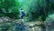 Man is crossing a river with a backpack. Male is hiking in nature.