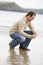 Man crouching on beach