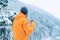 Man with cup drinking a hot drink dressed bright orange softshell jacket and enjoying snowy mountains landscape while he trekking