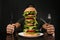 Man with cutlery eating huge burger