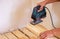 A man cuts a board with an electric saw. Repair of the floor in the house. Selective focus