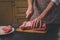 Man cuts of fresh piece of beef on a wooden cutting board in the home kitchen