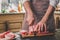 Man cuts of fresh piece of beef on a wooden cutting board in the home kitchen