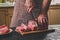 Man cuts of fresh piece of meat on a wooden cutting board in the home kitchen