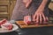 Man cuts of fresh piece of meat on a wooden cutting board in the home kitchen