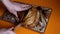 a man cuts fresh rye bread with flax on a cutting board with a knife and shows how fresh and soft it is