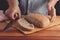 A man cuts freshly baked whole-wheat bran bread with a sharp knife