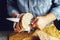 A man cuts freshly baked whole-wheat bran bread with a sharp knife