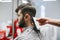 Man cuts hair in a men`s hairdresser and barber, a hairdresser cuts the hair with a clipper, close up. Process of creating a