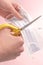 Man cuts a medical protective mask with yellow scissors on a pink background before throwing it away