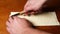 A man cuts a raw dough with a knife, on a wooden background. Homemade buns