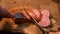 A man cuts a sausage on a wooden Board with a knife and fork