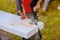 A man is cutting a board of wood with a jigsaw detail of a cutting wooden board with saw dust