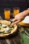 Man are cutting pizza with round knife. Tableware, juice in glasses, home interior, close-up