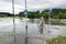 Man cycling and car trying to drive against flood on the street.