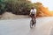 Man cyclist pedaling on a road bike outdoors in sun set