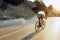 Man cyclist pedaling on a road bike outdoors in sun set