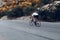 Man cyclist pedaling on a road bike outdoors in sun set