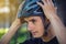 Man cyclist is wearing a sports gray helmet on his head in the background of green nature.