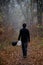 Man in dark clothing walks among autumn foggy forest, with balloons, black and white. Concept of choice, considering