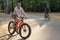 A man in dark glasses rides a bicycle in a public park in the summer. Sports and leisure