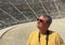 A man in dark glasses and a yellow T-shirt stands on the steps of the Ancient Theater of Epidaurus. Sanctuary of Asclepius at