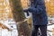 Man in a dark jacket cuts a tree with the help of an electric chainsaw. Deforestation. Harvesting wood. Scaffolding