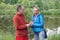 Man on a date gives  woman a bell flower in the summer in a park on the lake shore