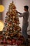 Man decorating beautiful Christmas tree at home