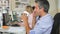 Man At Desk With Mobile Phone Drinking Coffee