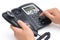 Man dialing a black telephone on white background