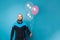 Man in diver suit making funny face and holding birthday balloons against blue studio wall banner background