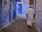 Man with djellaba walking through the streets of the medina of chefchaouen, village of Morocco