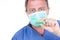 Man doctor chemist hand in blue protective mask hold green test tube white background