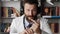 Man doctor with headphones speaks into camera. Bearded male doctor in white coat looking at camera and explains