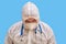 Man doctor medic in a protective suit uniform with goggles and face mask on a studio blue background. Paramedic in white antiviral